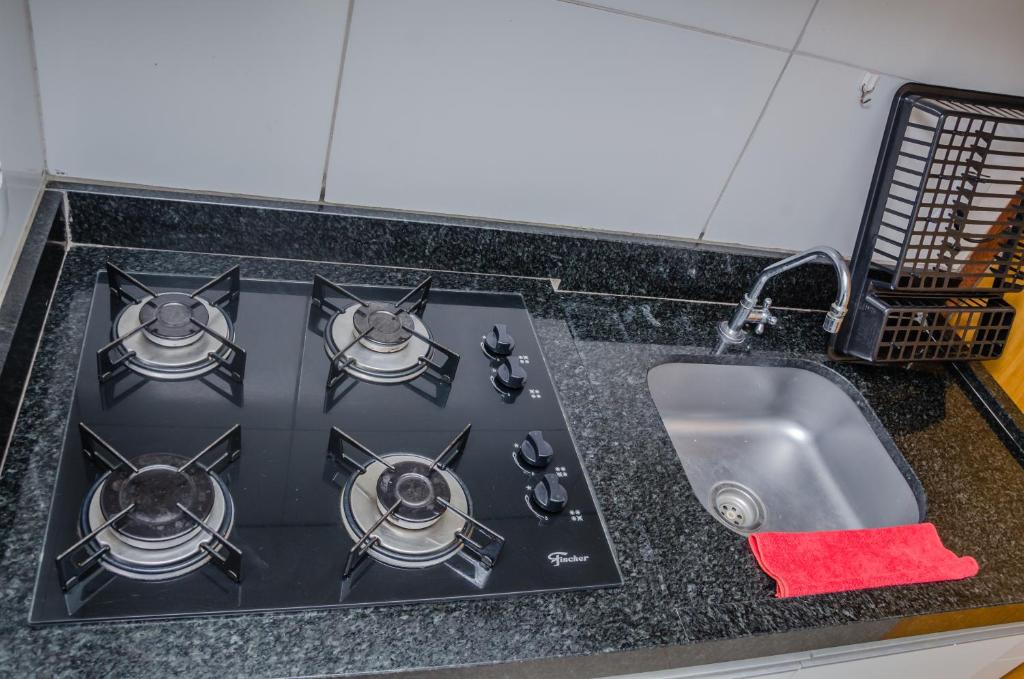 a kitchen counter with a stove and a sink at Apto 2 qts, wifi, netflix, metrô próximo in Brasília