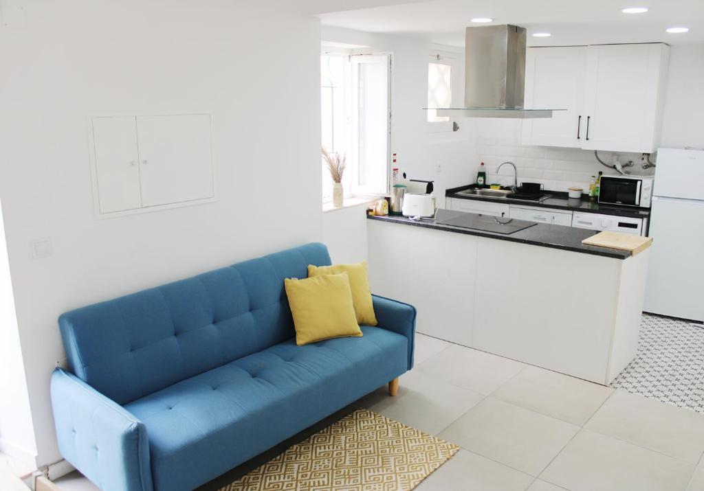 a blue couch in a room with a kitchen at Casa das Nobres in Évora