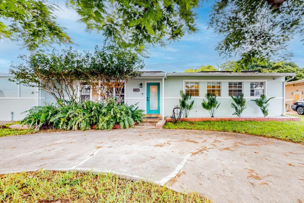 a white house with a blue door at Miami Gardens Getaway in Miami Gardens