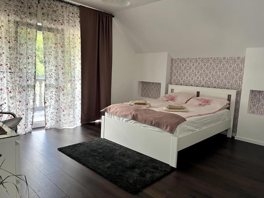 a bedroom with a bed with pink sheets and curtains at Forest Lux in TÄƒuÅ£ii MÄƒgheruÅŸ