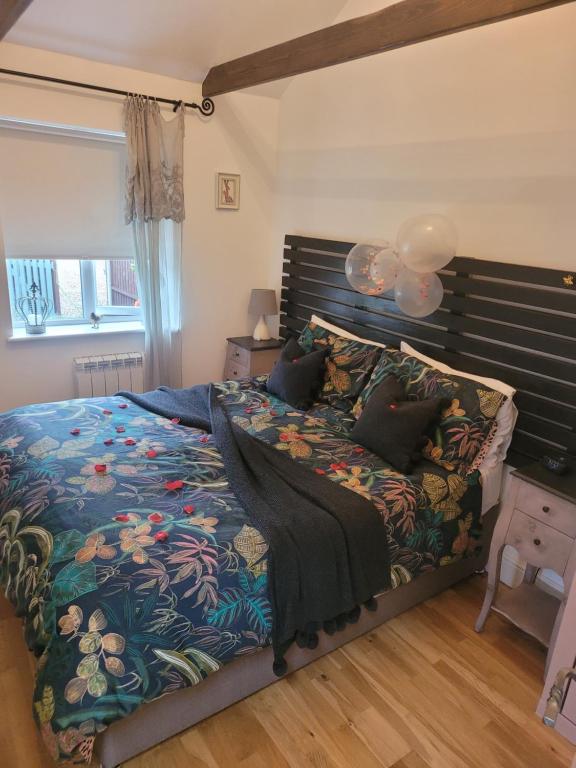 Un dormitorio con una cama grande con cabecero de madera. en Birch Cottage with private wood fire hot tub, en Harrietsham