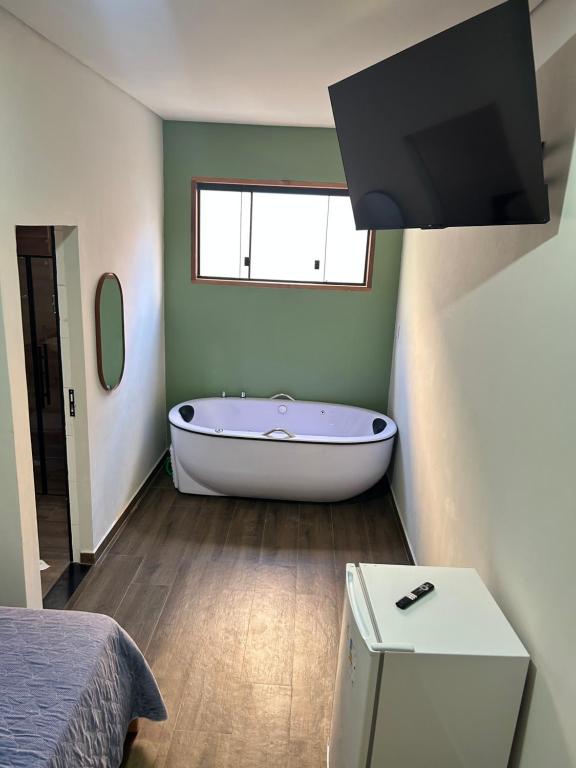 a bathroom with a bath tub and a window at Hotel Chão Mineiro in São Thomé das Letras
