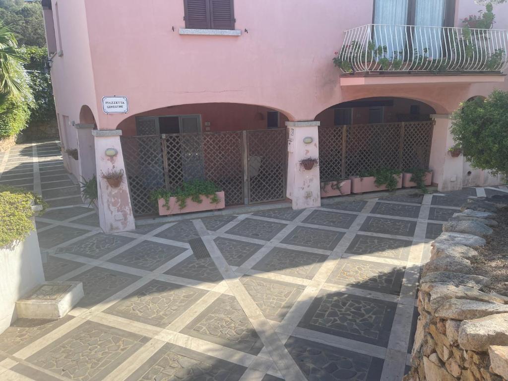 a pink house with a gate and a courtyard at Piazza ginestre porto rotondo in Porto Rotondo