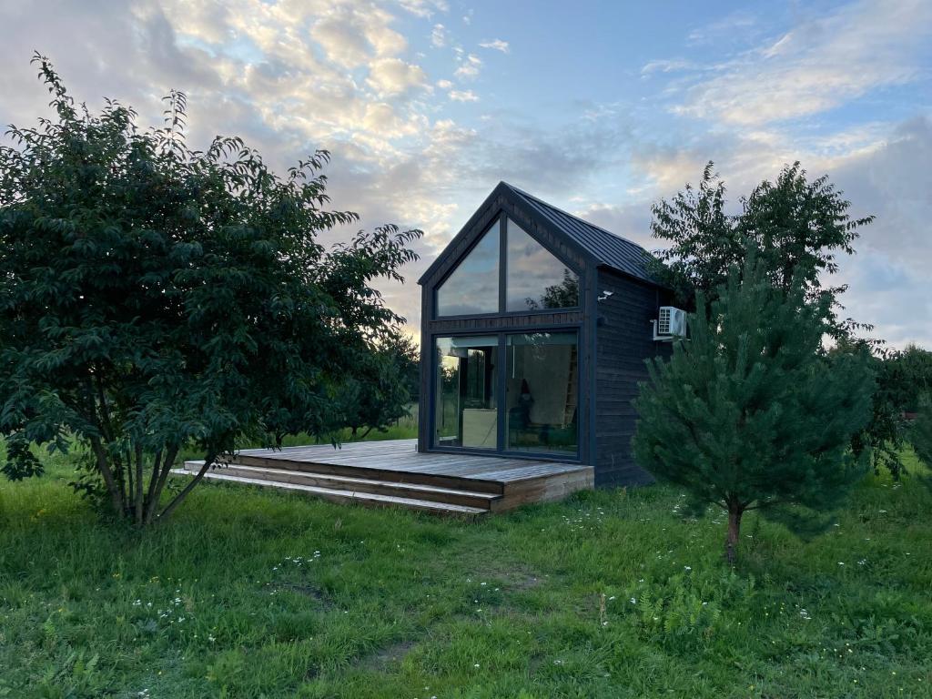 uma pequena casa com janelas de vidro num campo em Your Cute Hytte em Smoldzino