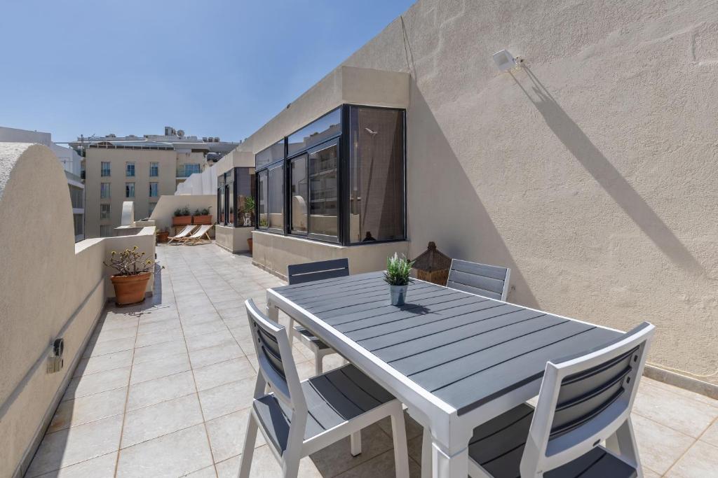 una mesa y sillas en el balcón de una casa en Large Terrace Penthouse Sliema, en Sliema
