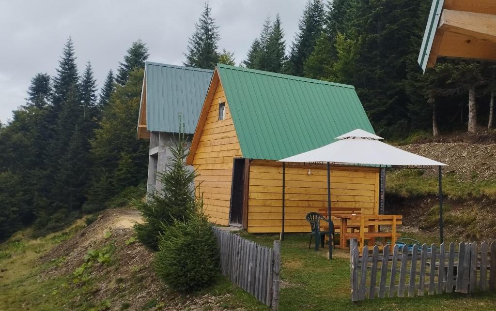 una casa con una mesa y un techo verde en KOMOVI- kobildo SMJESTAJ, en Andrijevica