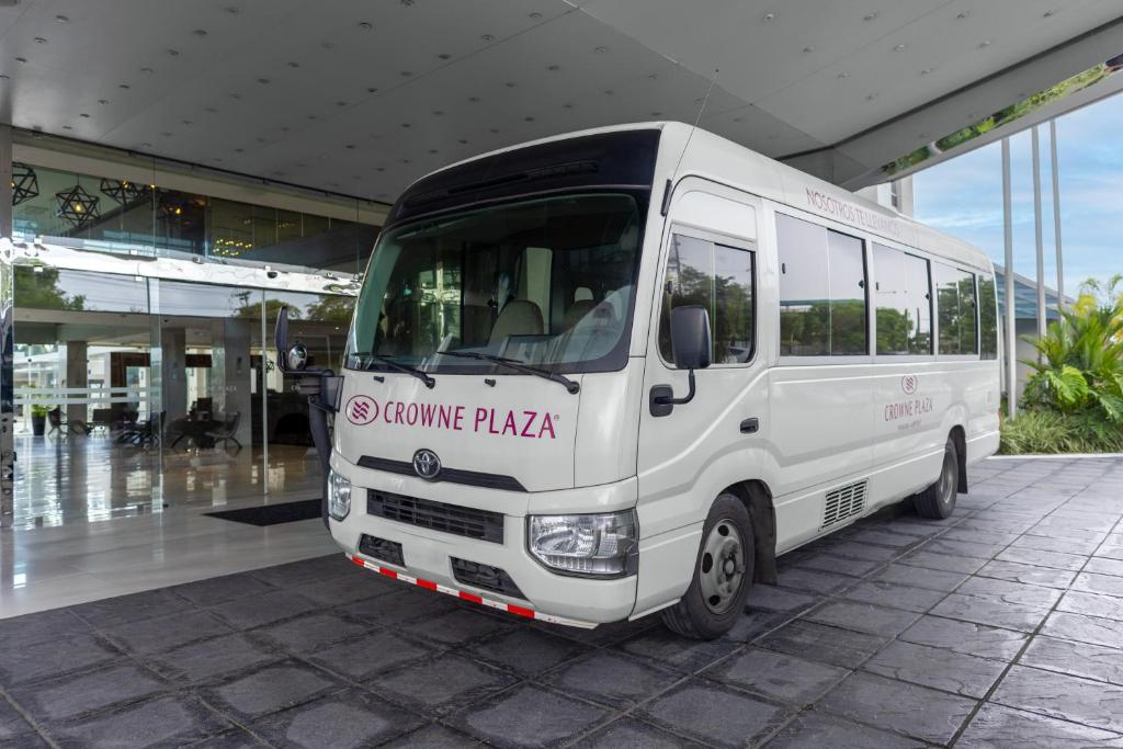 a white bus parked in front of a building at Crowne Plaza Airport by IHG in Tocumen