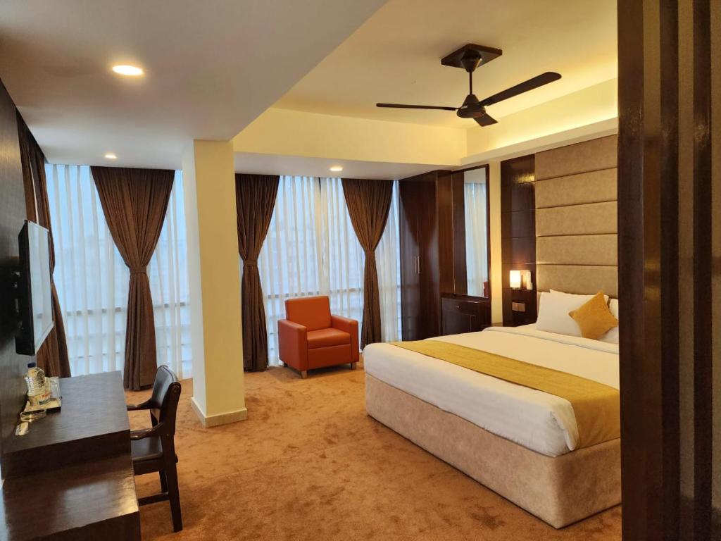a bedroom with a bed and a desk and a chair at White Park Hotel & Suites in Chittagong