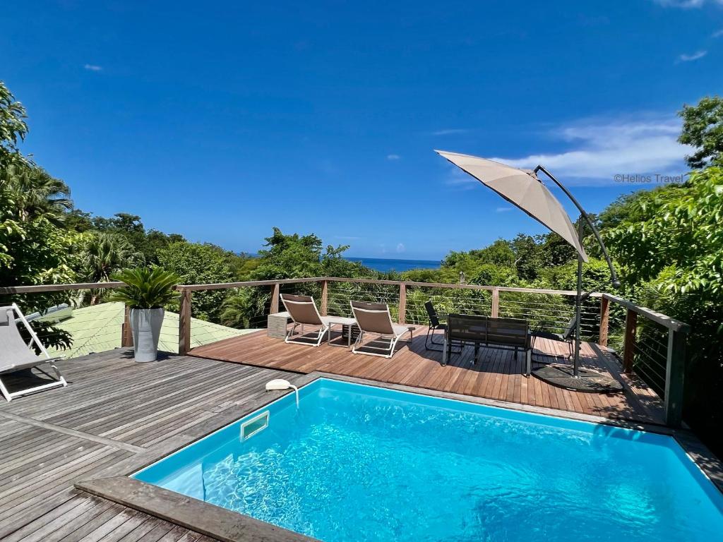ein Pool auf einer Terrasse mit einem Sonnenschirm in der Unterkunft Case Coco Pointe Batterie. Piscine, vue mer, 4 p. in Deshaies