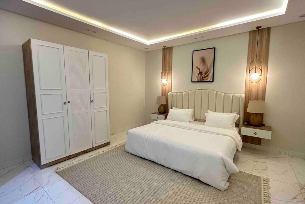 شقة حي العقيق قريبة البوليفارد في الرياض: غرفة نوم مع سرير أبيض كبير وخزانة