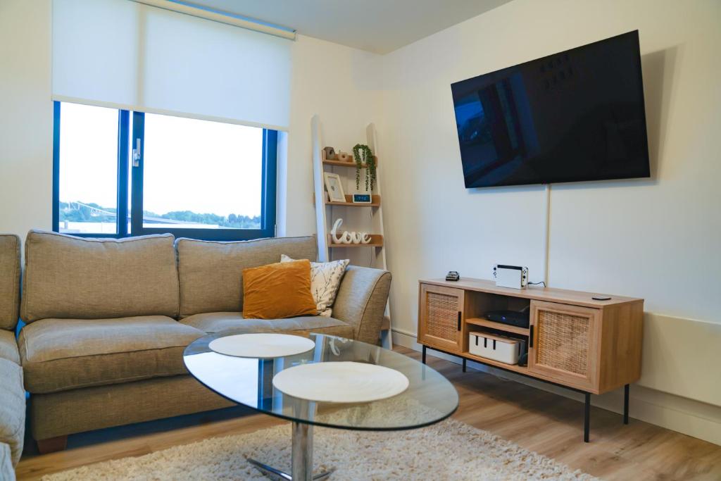 a living room with a couch and a flat screen tv at Luxe Apartment: 3 mins Luton Airport & Free Wi-Fi in Luton