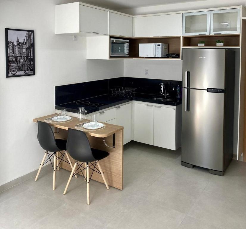 a kitchen with a refrigerator and a table and chairs at AP822 ar condicionado piscina academia coworking etc in Juiz de Fora