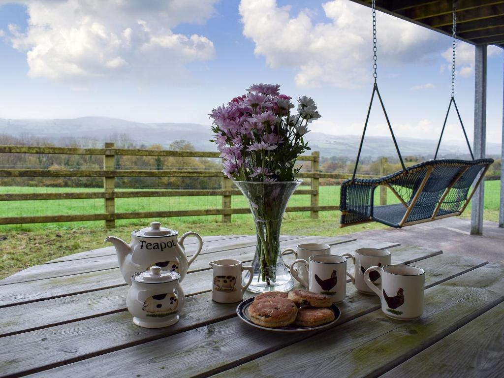 a table with cups and a vase with flowers and cookies at Penybryn in Llansadwrn