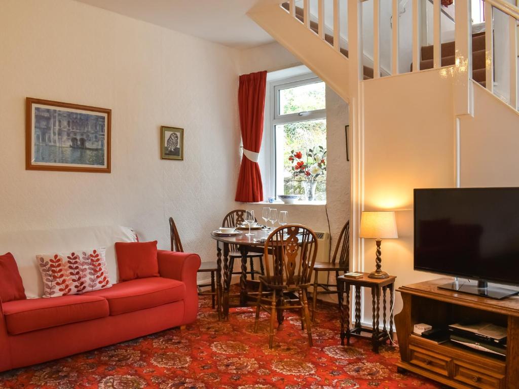 sala de estar con sofá rojo y TV en Kiln Cottage, en Bolton le Sands