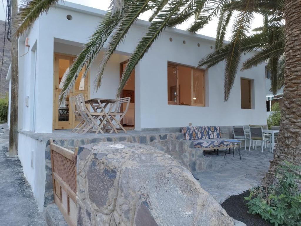 una casa blanca con una palmera delante de ella en La Casita a 60 pasos del mar en Tamaduste