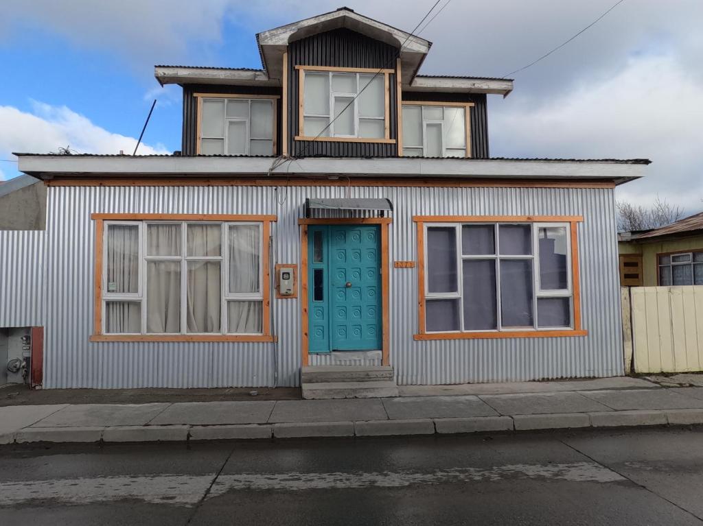 a house with a blue door and windows at Hostel 53 Sur in Puerto Natales