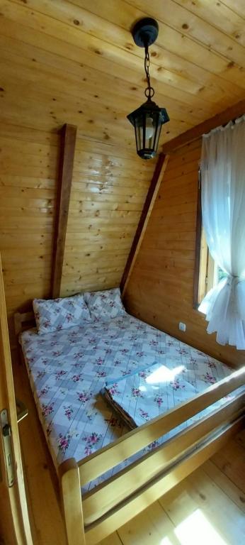 a bed in a log cabin with a window at Odmor in Šavnik