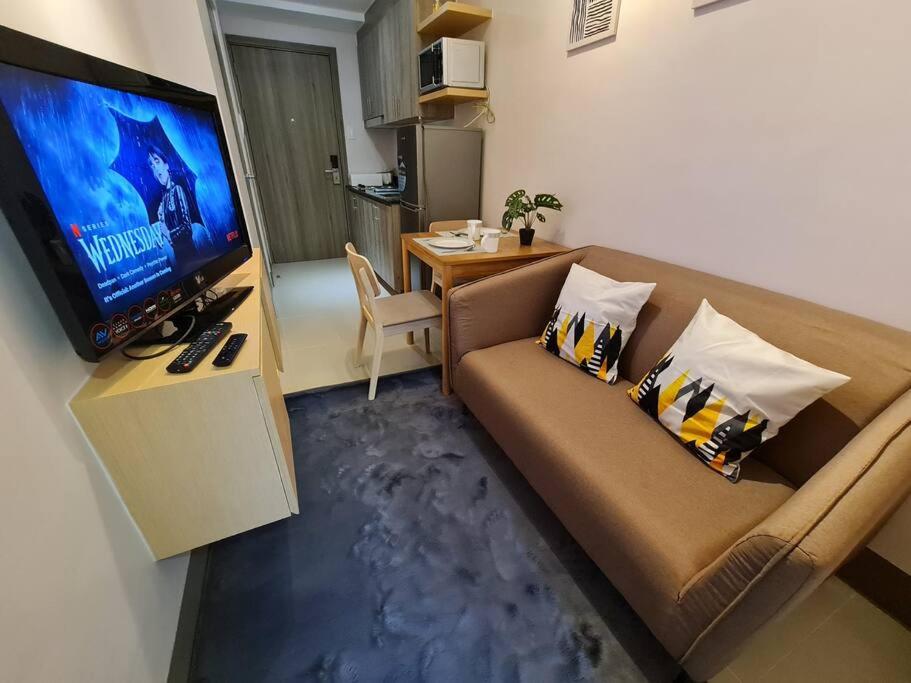 een woonkamer met een bank en een flatscreen-tv bij Chic 2 BR EDSA APT w/ Balcony Netflix Prime Video in Manilla