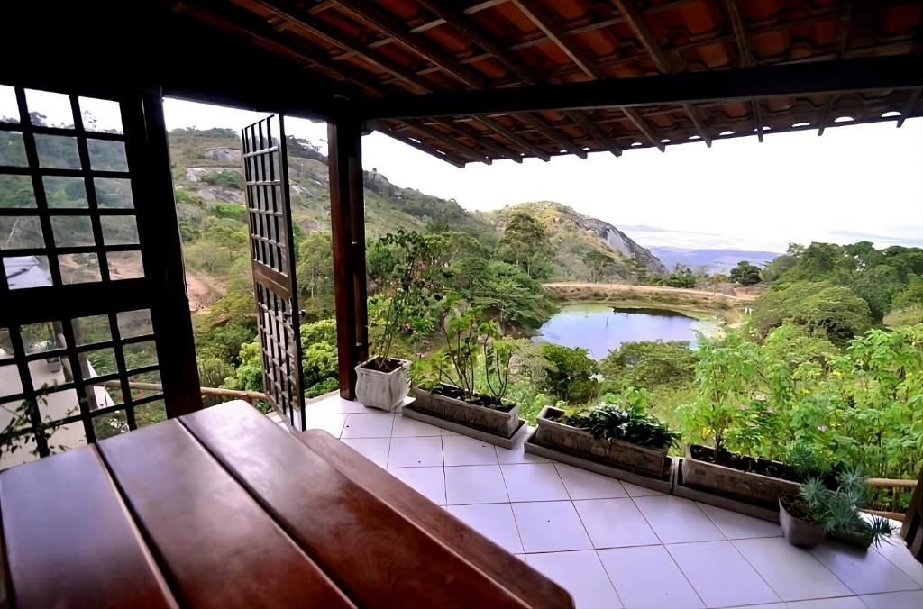 uma varanda com uma mesa e vista para um rio em Refúgio Serra Negra - PE em Bezerros