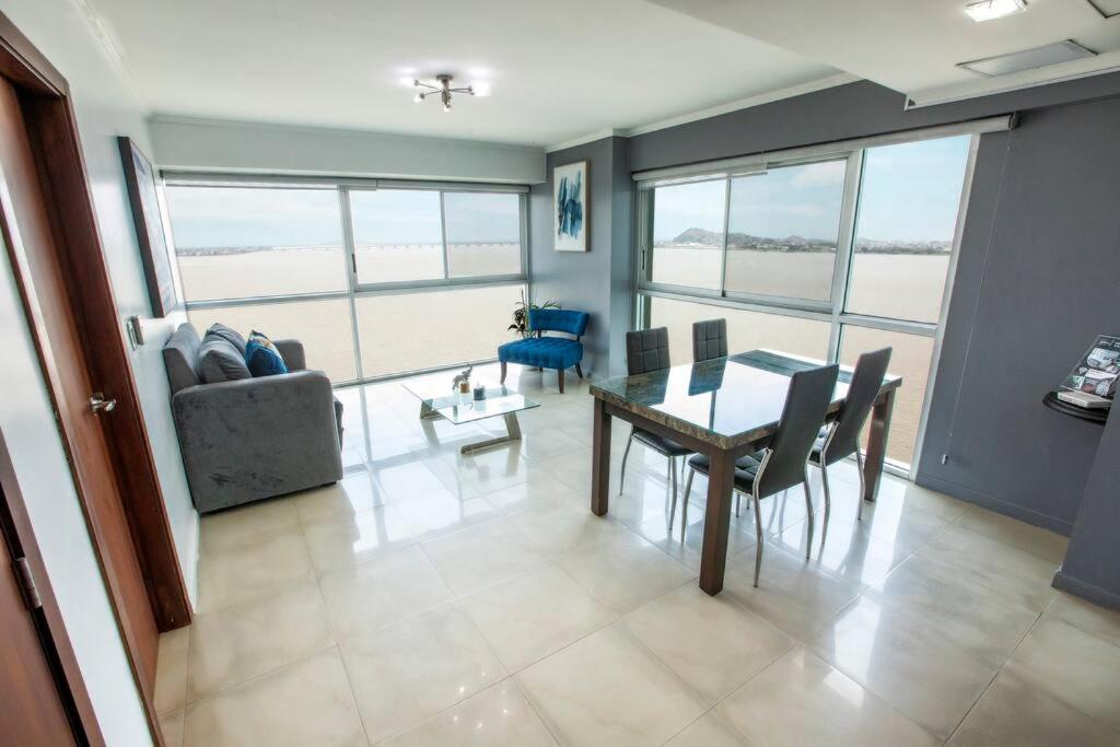 een woonkamer met een tafel en een bank bij Suit 906 hermosa vista panorámica al Rio, Piscina. in Guayaquil