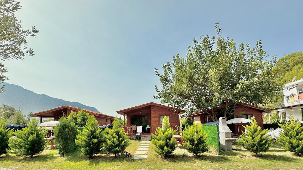una casa con un patio con árboles y edificios en Hurmalık Apart Evleri-Very Close to the Sea Large Garden Bungalow with Barbecue and Swing, en Karaoz
