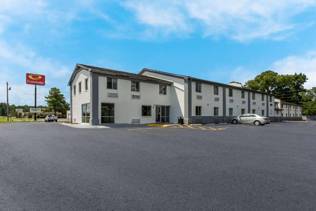 a white building with a car parked in a parking lot at Econo Lodge Cherry Point in Havelock