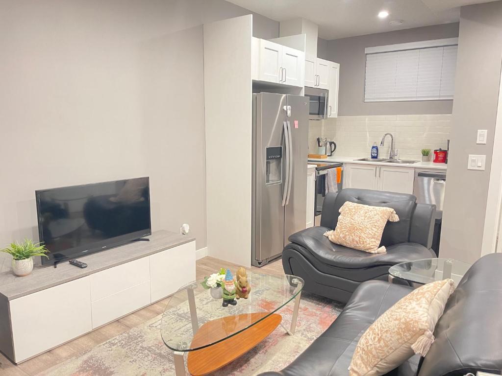 a living room with a tv and a couch and chairs at Cozy basement suite in Calgary