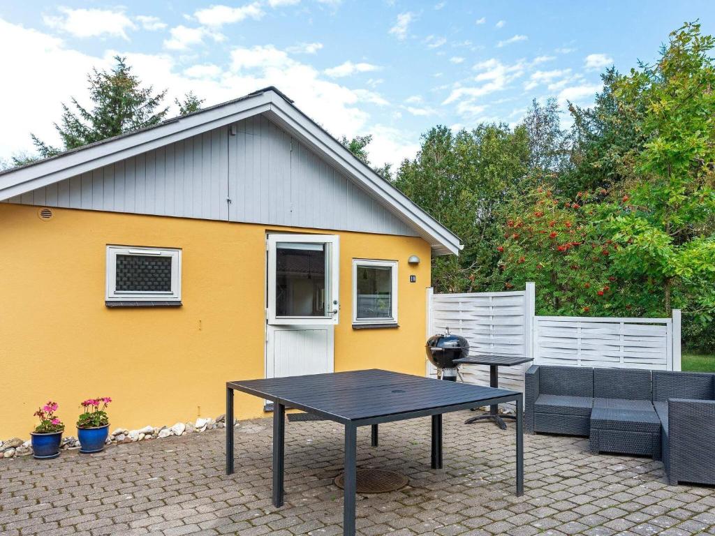 a patio with a table and a yellow house at 4 person holiday home in Hurup Thy-By Traum in Sønder Ydby