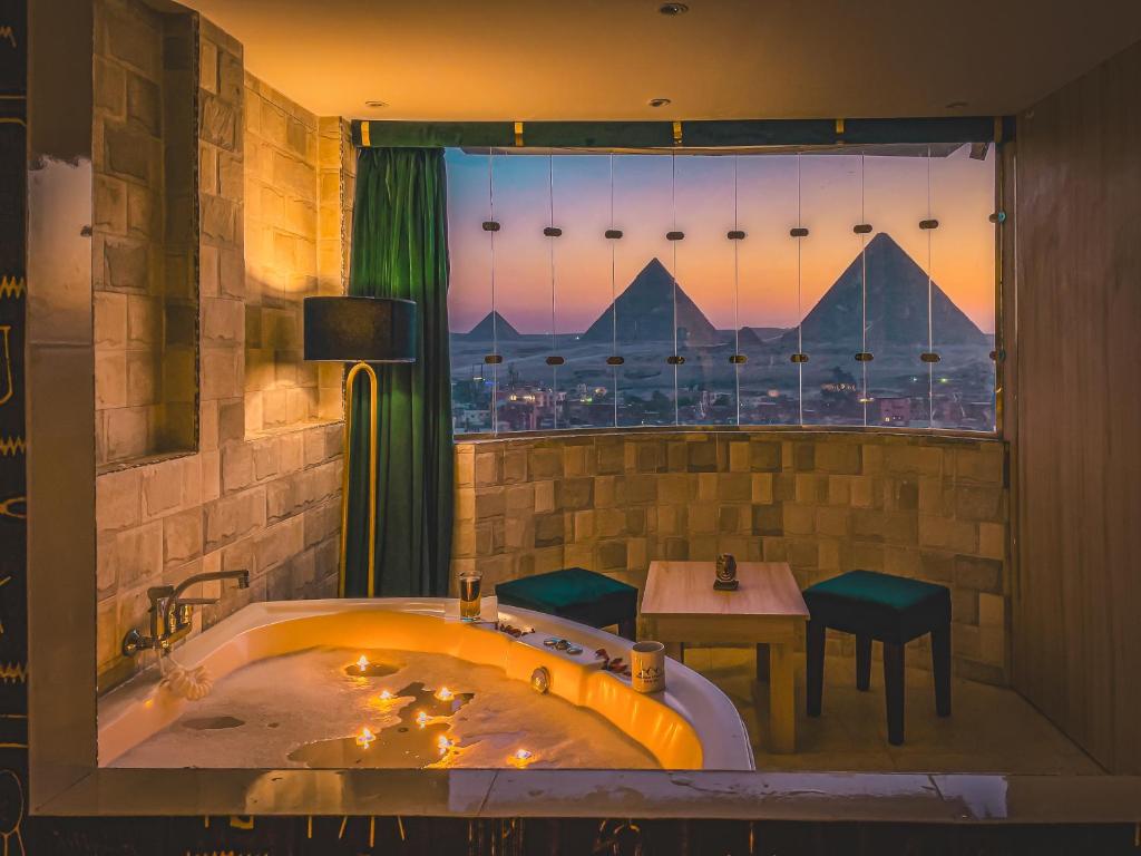 La salle de bains est pourvue d'une baignoire, d'une table et d'une fenêtre. dans l'établissement Jumeirah pyramids view inn, au Caire