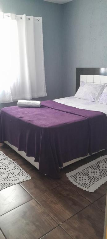um quarto com uma cama com um cobertor roxo em Meire Hostel em Guarulhos