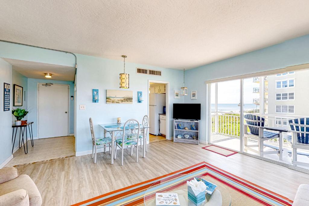 a living room with a table and chairs and a balcony at Turtle Time Suite in Satellite Beach