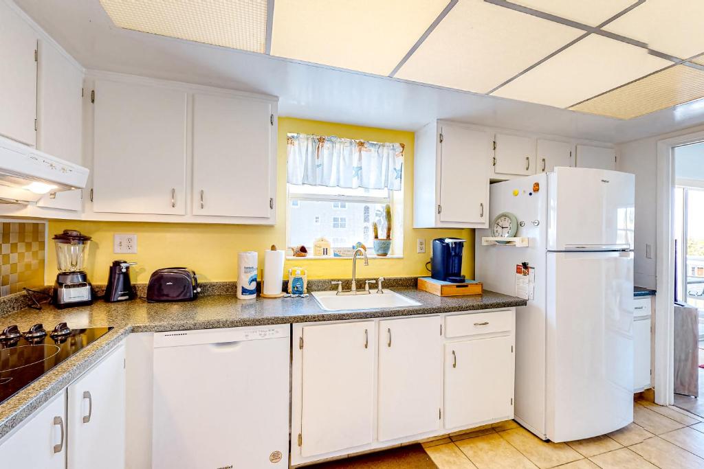a kitchen with white cabinets and a white refrigerator at Turtle Time Suite in Satellite Beach