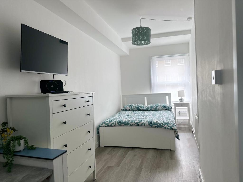 a bedroom with a bed and a dresser with a tv at High Barnet Studio Flat in Barnet