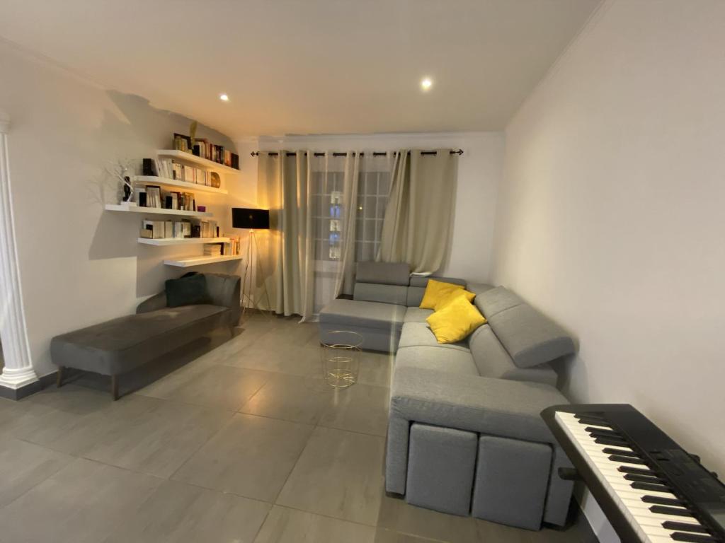 uma sala de estar com um sofá e um piano em Maison Lyon-Bron Eurexpo - Stadium Groupama em Bron