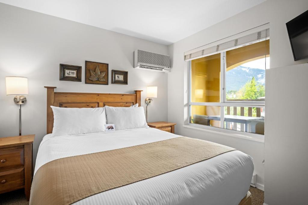 een slaapkamer met een groot bed en een raam bij Bear Lodge One Bedroom by MVA in Whistler