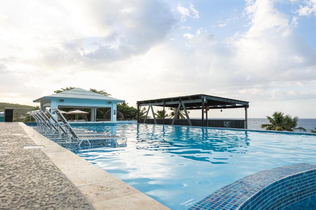 a swimming pool with chairs and a gazebo at Hotel El Guajataca in Quebradillas