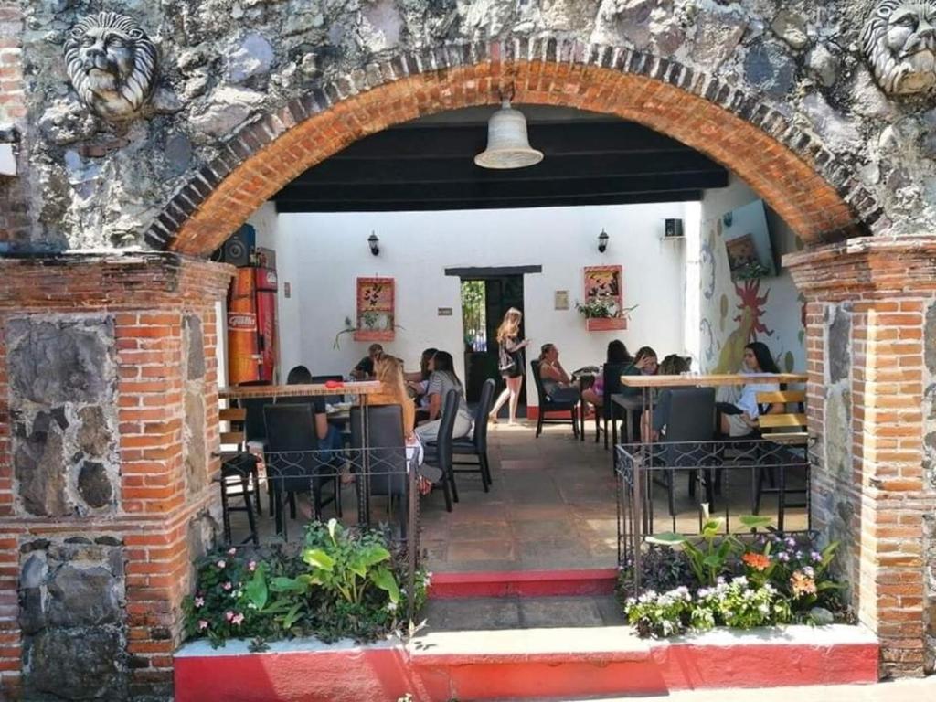 Un arco en un restaurante con gente sentada en las mesas en Hostel Hopa Antigua, en Antigua Guatemala