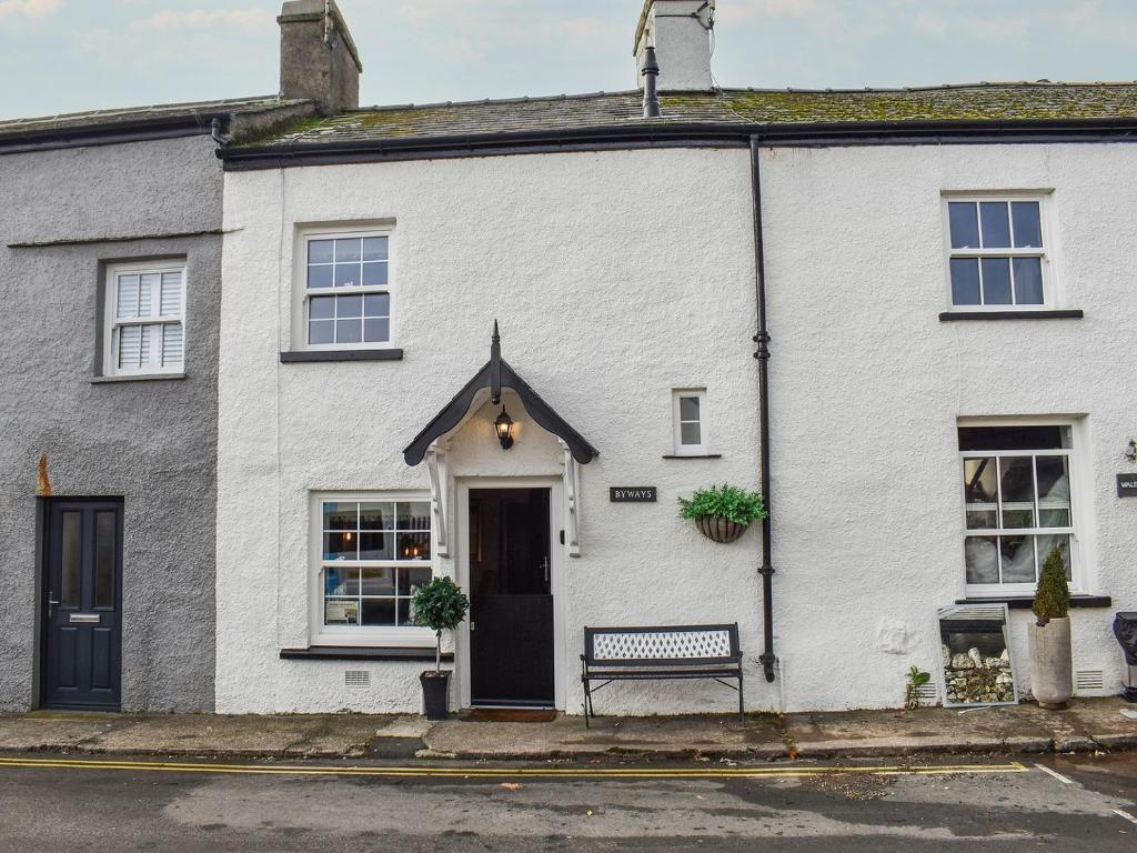 a white house with a bench in front of it at Byways in Cartmel