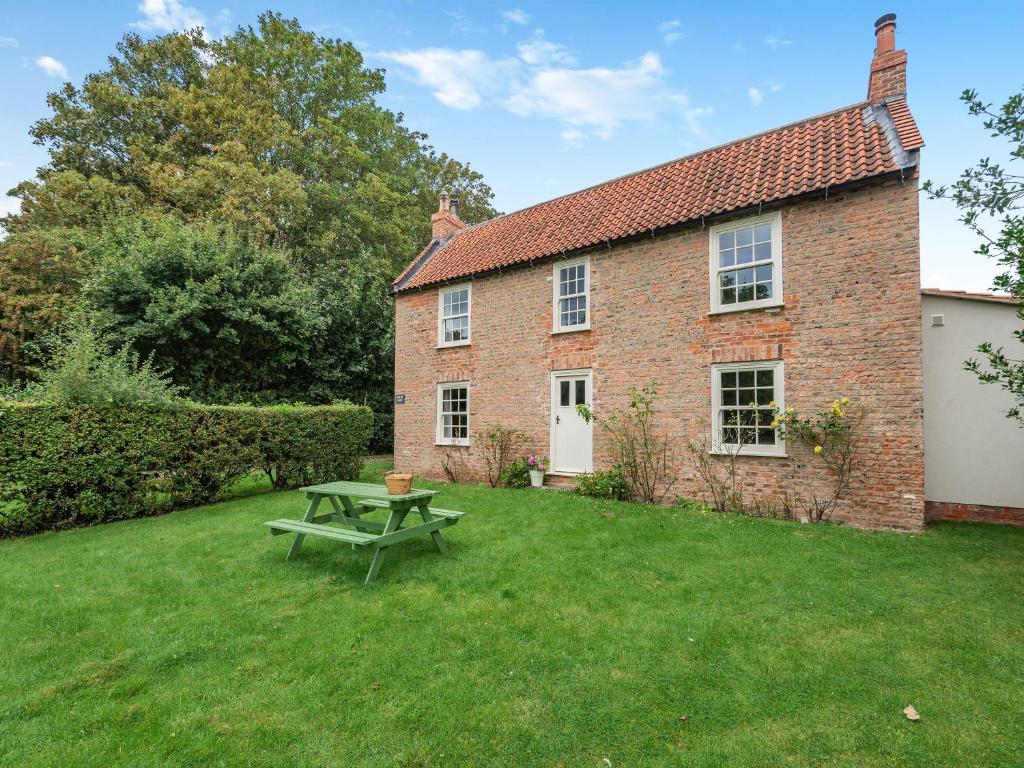 a brick house with a picnic table in the yard at Peaceful Farmhouse - Uk44787 in Grainthorpe