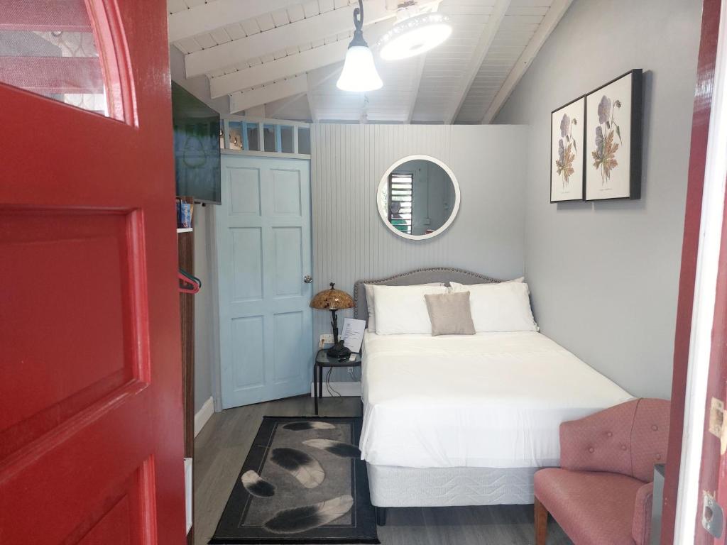 a bedroom with a white bed and a red door at Carmen's Cozy Studio in Bridgetown