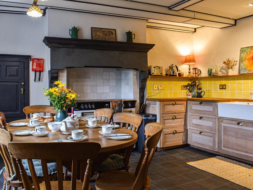 cocina con mesa con sillas y chimenea en Needle House en Ravenstonedale