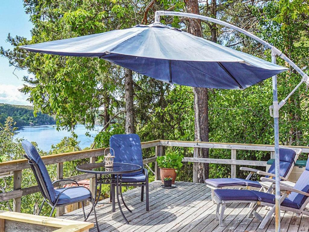 eine Terrasse mit einem Tisch, Stühlen und einem Sonnenschirm in der Unterkunft Holiday home TYRESÖ V in Tyresö