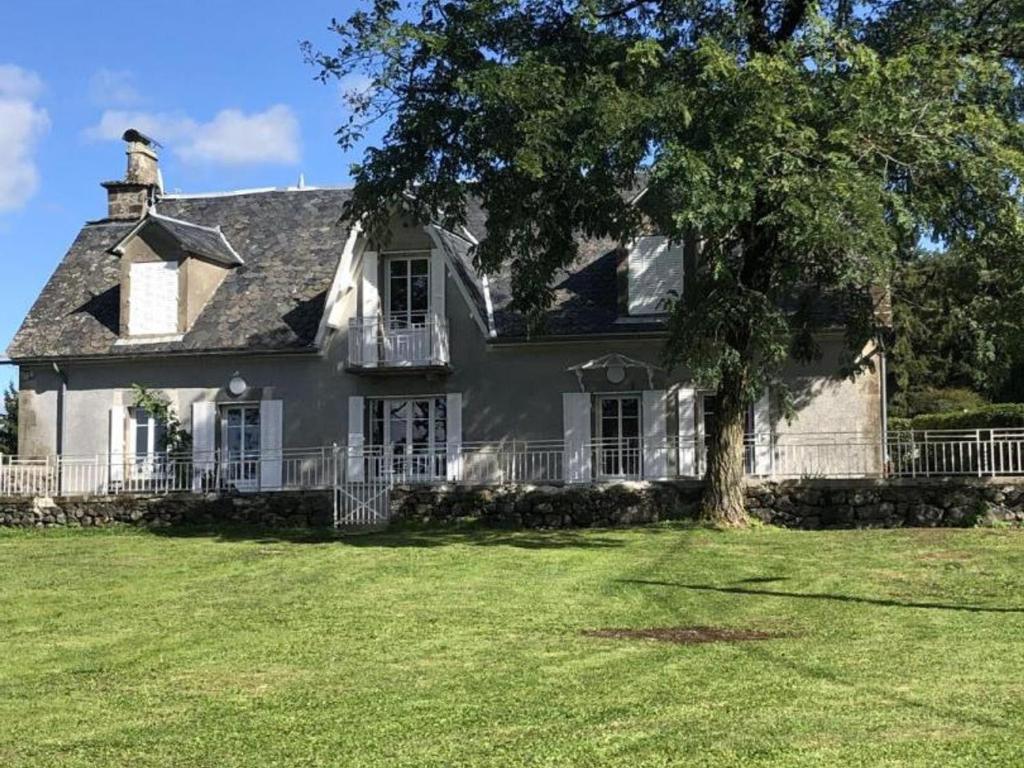 a large white house with a tree in the yard at Gîte Saint-Bonnet-de-Salers, 5 pièces, 9 personnes - FR-1-742-288 in Saint-Bonnet-de-Salers