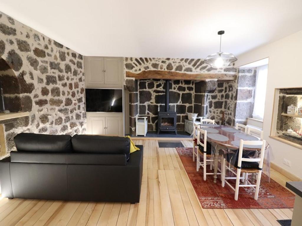 a living room with a black couch and a stone wall at Gîte Fontanges, 4 pièces, 6 personnes - FR-1-742-413 in Fontanges