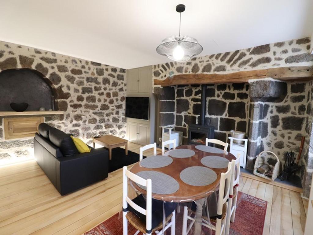 a living room with a table and a stone wall at Gîte Fontanges, 4 pièces, 6 personnes - FR-1-742-413 in Fontanges