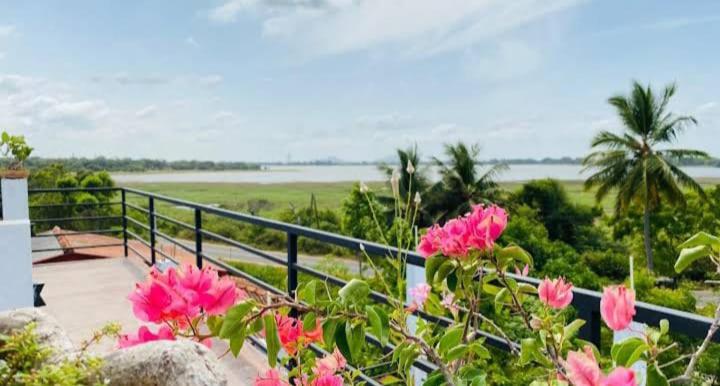 a balcony with pink flowers and a view of the ocean at Lake Edge Resort in Anuradhapura