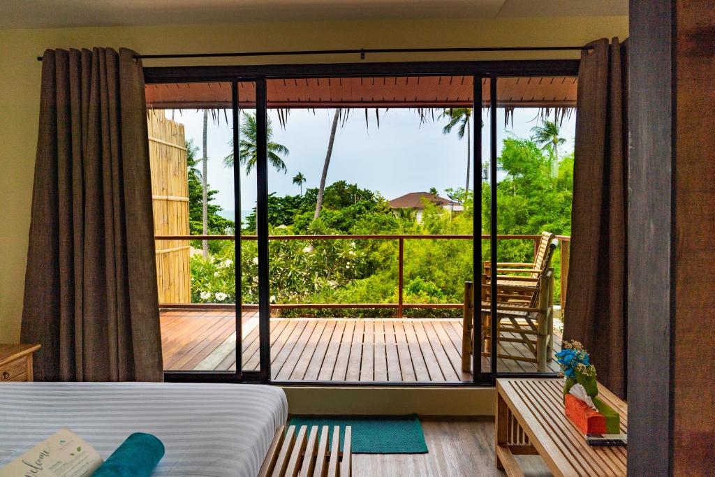 a room with a bed and a balcony with a view at Sea Dance Resort in Choeng Mon Beach