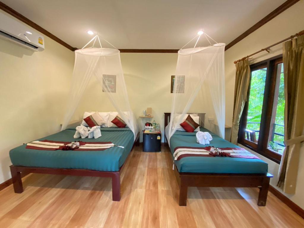 Khao Sok River & Jungle Bungalow في خاو سوك: غرفة نوم بسريرين توأم في غرفة