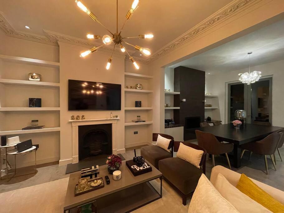 a living room with a fireplace and a dining room at Quintessential Town House Close to Central London in London