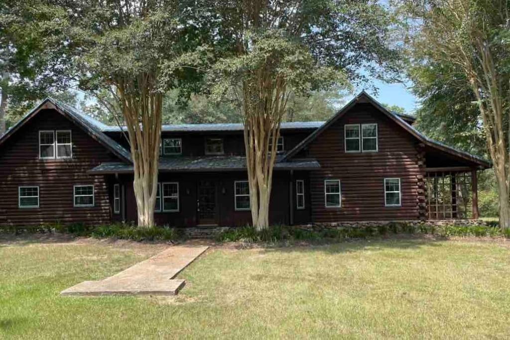 uma grande casa de madeira com árvores em frente em Journey Hope Cabin em Magnolia
